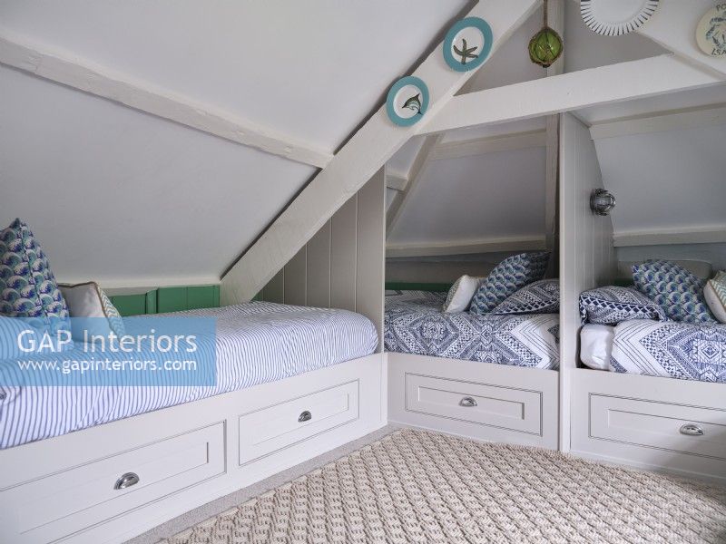 Chambre loft aérée avec lits à thème côtier bleu et blanc et rangement intégré