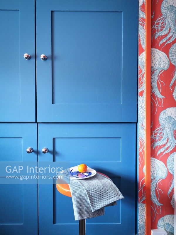 Unités de cuisine bleues modernes avec un papier peint inspiré de la mer et un tabouret orange