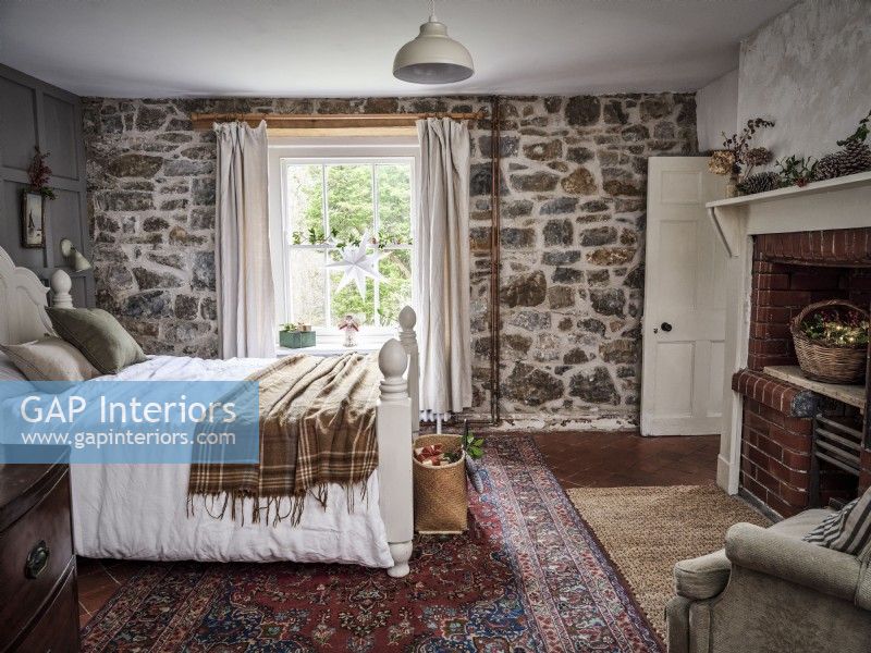 Chambre à coucher campagnarde avec mur de pierre et tapis rustique