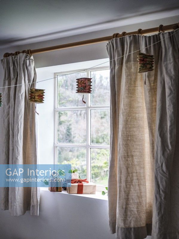 Fenêtre avec décorations suspendues et rideaux beiges