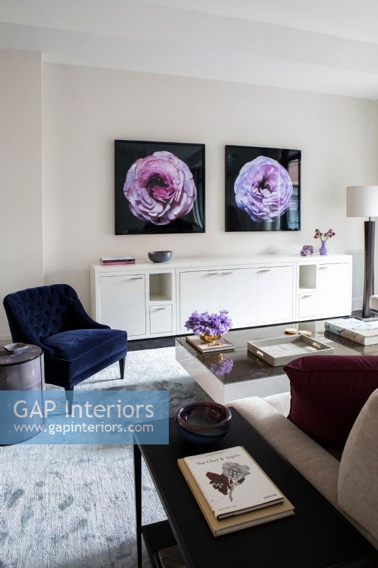Salon moderne avec une longue crédence blanche décorée de photographies de fleurs au mur.