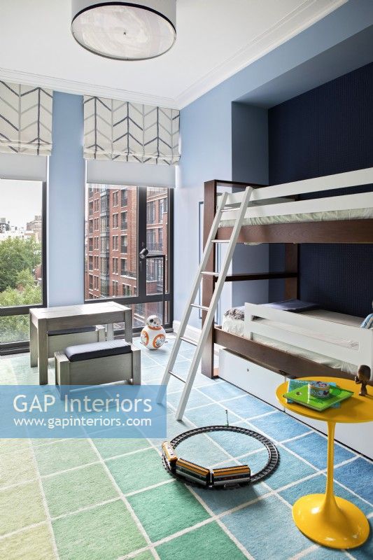Chambre bleue pour garçons avec lits superposés et grandes fenêtres avec vue sur la ville.