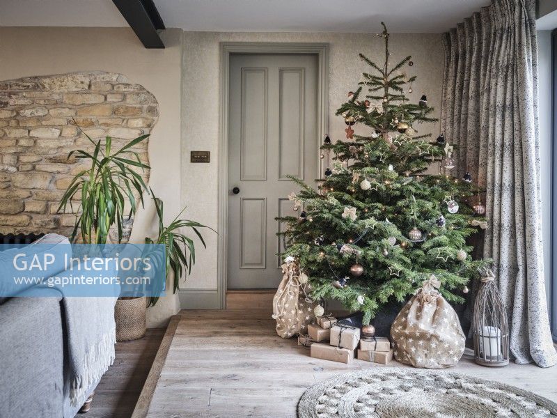 Salon neutre avec briques apparentes et arbre de Noël avec des cadeaux