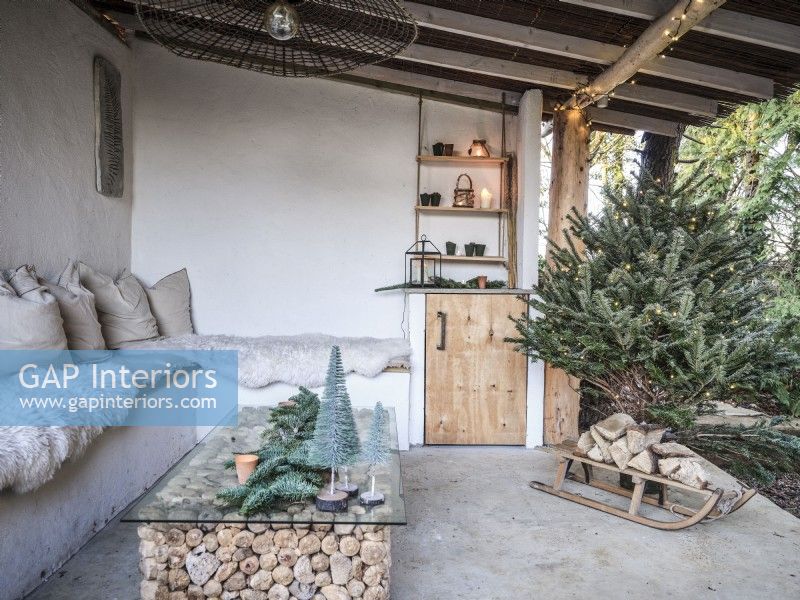 Espace extérieur avec décor de Noël et bûches empilées sous la table basse
