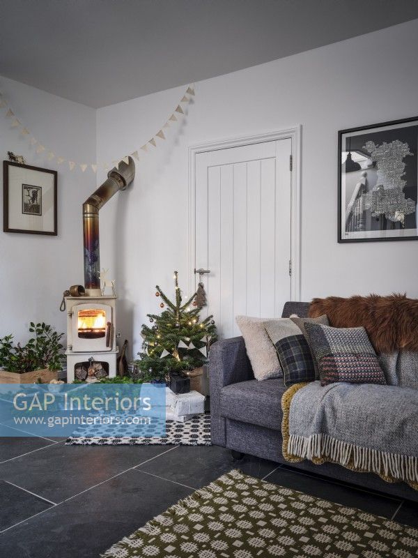 Salon nordique avec canapé, arbre de Noël et poêle à bois