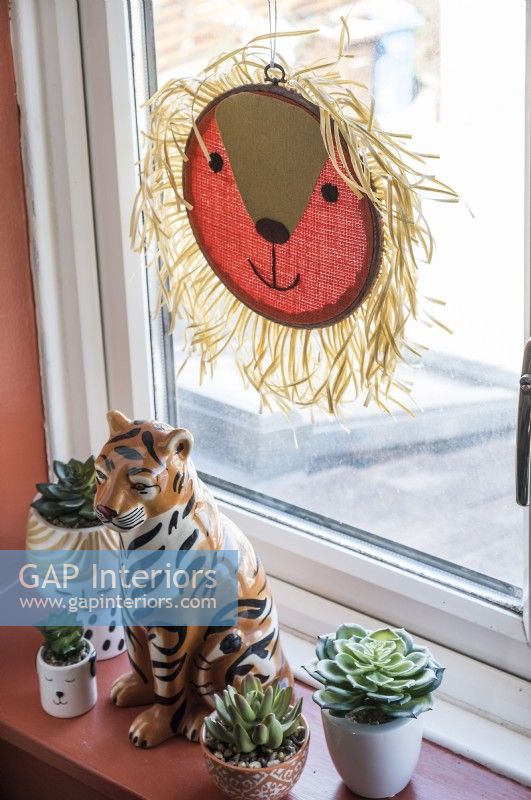 Ornements de lion et de tigre sur le rebord de la fenêtre avec de petites plantes succulentes