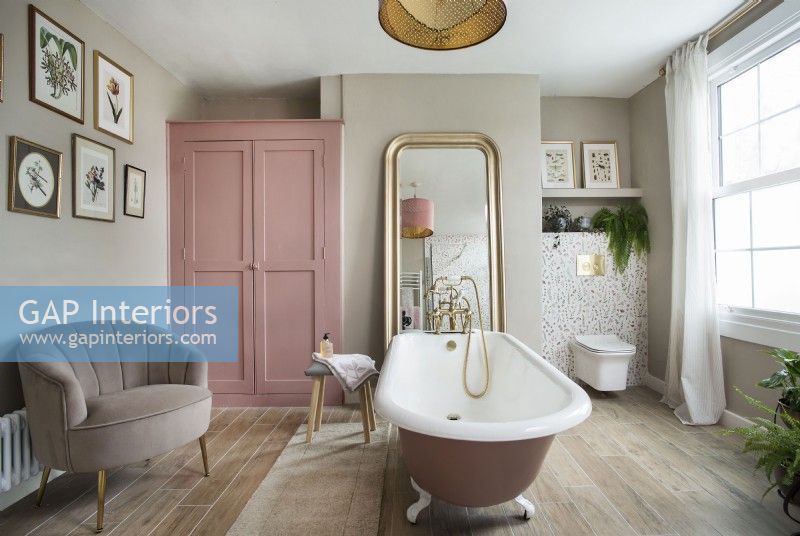 Salle de bain féminine de style vintage avec baignoire à roulettes rose et armoire
