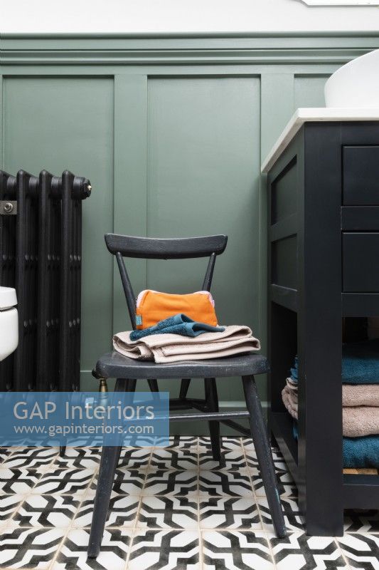 Détail d'une petite chaise de salle de bain sur un sol en carrelage à motifs monochromes