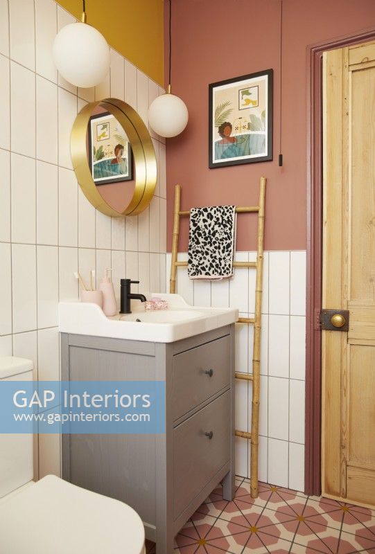 Salle de bain avec sol en vinyle coloré, carrelage blanc et murs peints en jaune et rose.