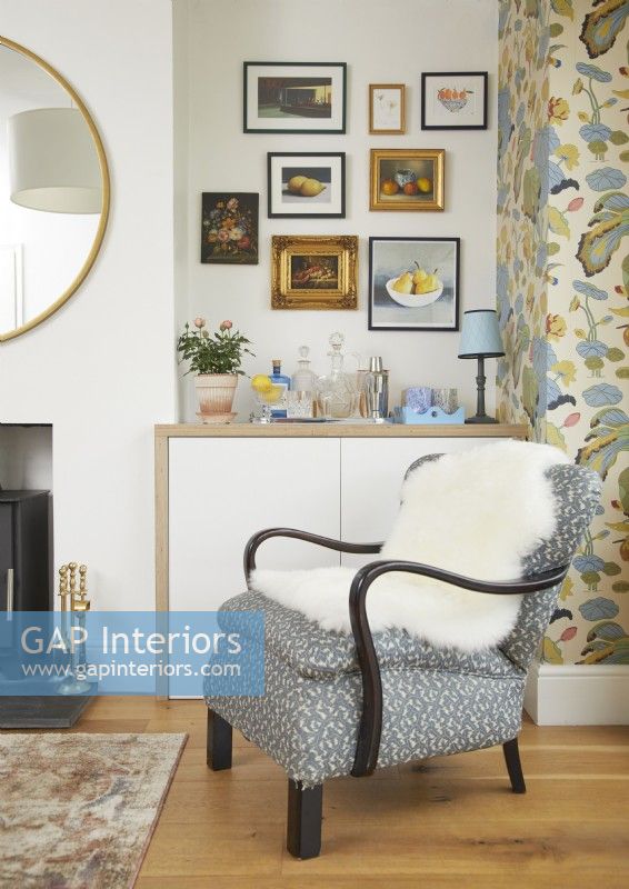 Salon avec fauteuil rétro, coin boissons et peintures à l'huile vintage au mur.