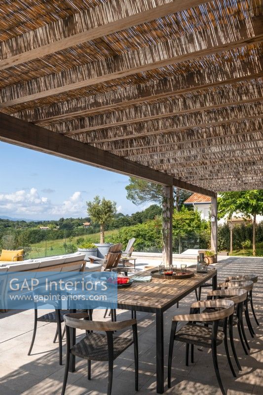 Salle à manger extérieure ombragée sur terrasse avec vue panoramique en été