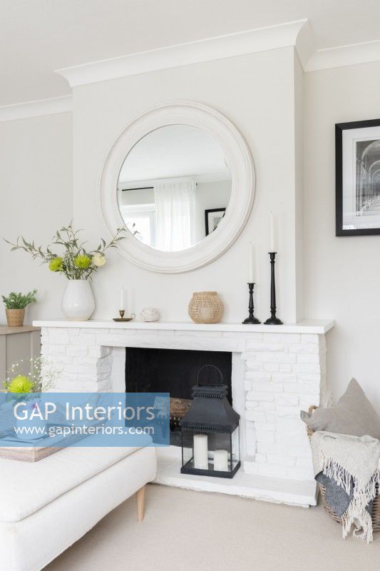 Miroir rond et cheminée en brique peinte en blanc dans un salon neutre moderne