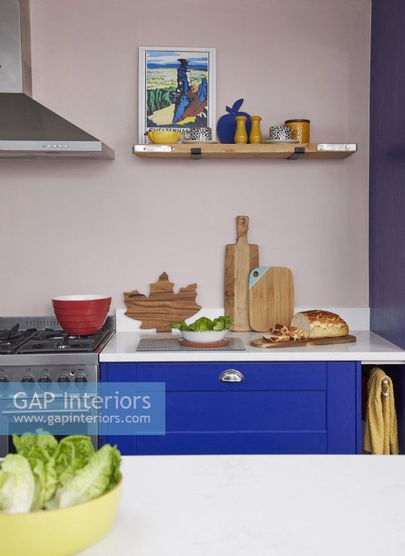 Détail de cuisine coloré avec armoires bleu cobalt et étagères ouvertes.