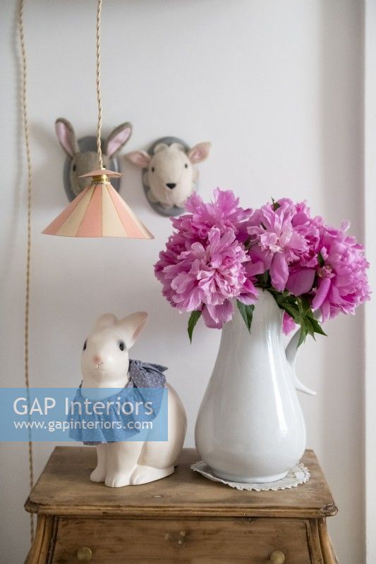 Fleurs roses dans un vase blanc et ornements d'animaux dans la chambre d'enfant