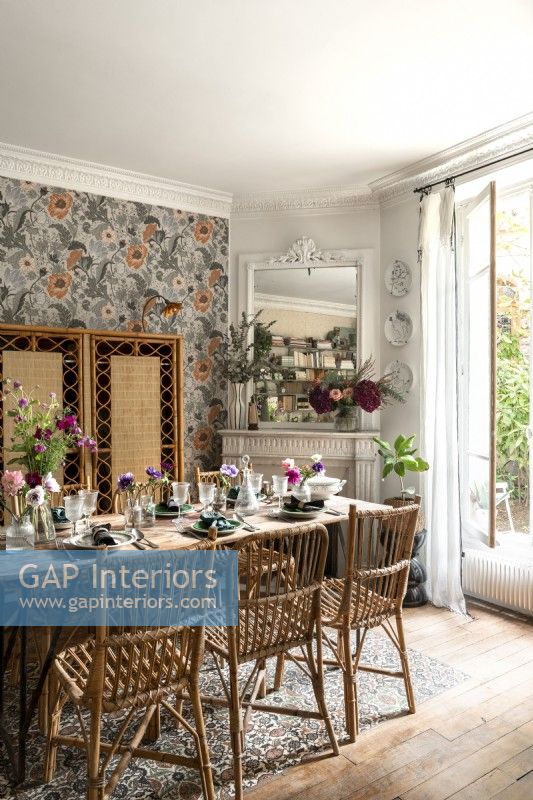 Salle à manger éclectique avec meubles en osier et papier peint floral
