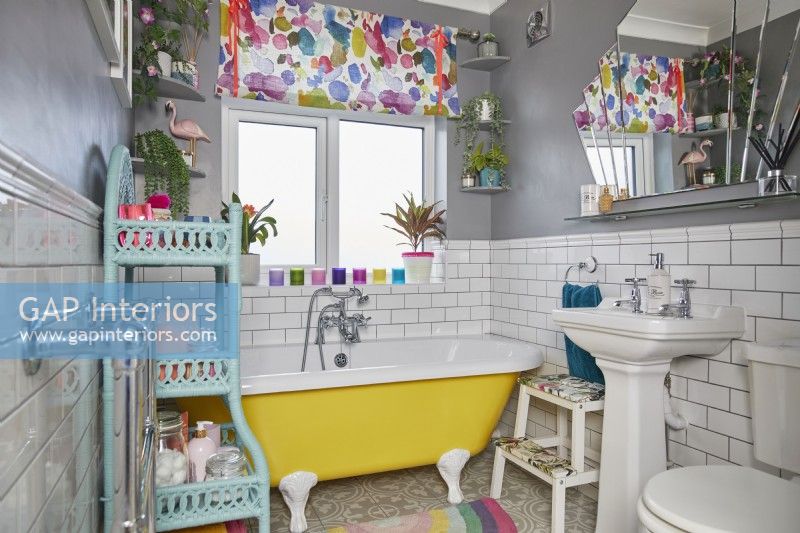 Salle de bain colorée avec baignoire autoportante jaune, carrelage métro blanc et murs gris.