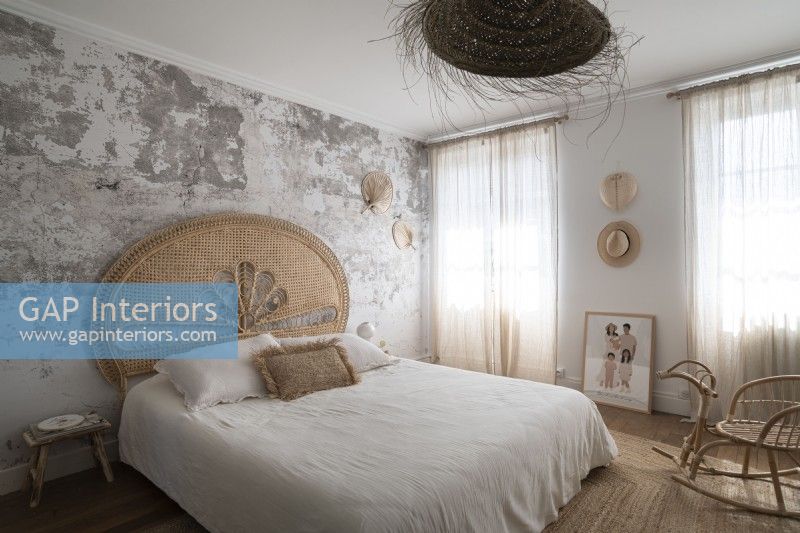 Chambre de campagne moderne avec mur de plâtre nu et tête de lit en rotin