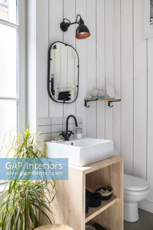 Petit lavabo et miroir dans la salle de bain aux murs en bois blanc