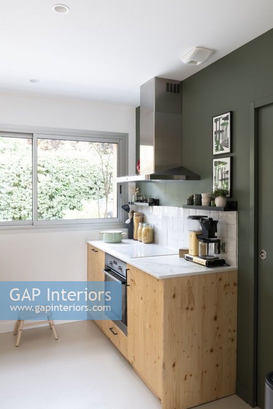 Unité en bois contre un mur peint en vert foncé dans une cuisine moderne