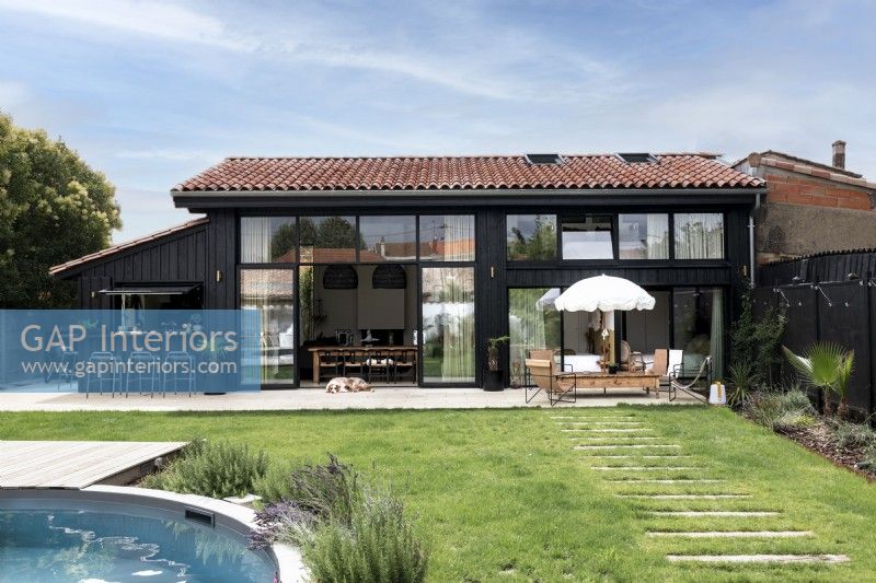 Extérieur de maison moderne avec pelouse à côté de la piscine