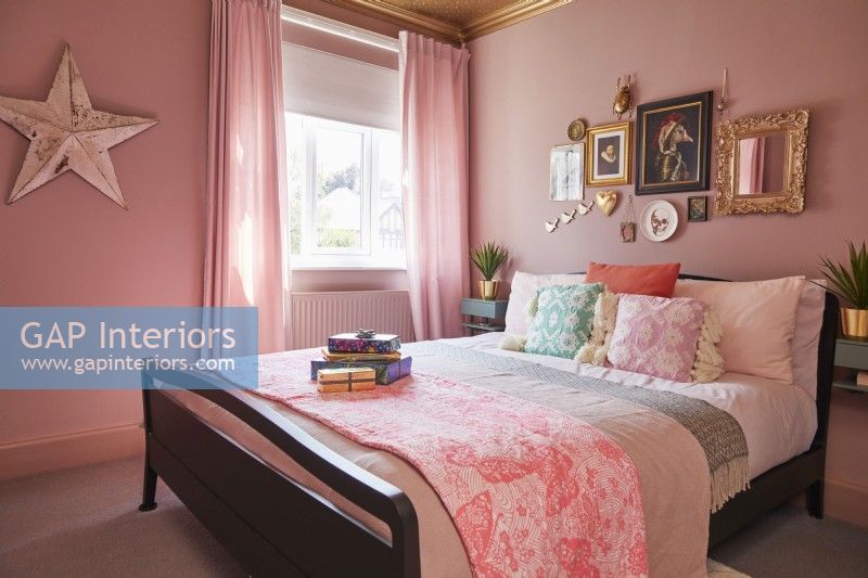 Bedroom with double bed, pink painted walls with framed pictures and a star decoration.