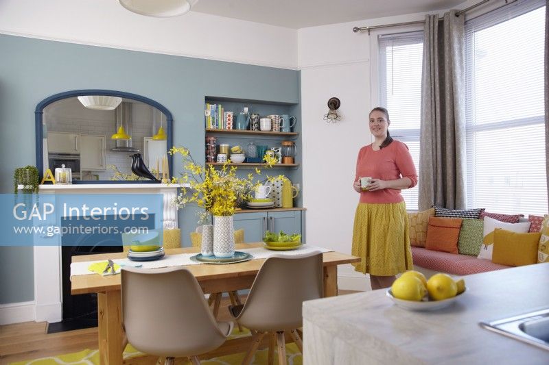 Cuisine-salle à manger ouverte avec des murs bleus, une cheminée victorienne et des sièges près de la fenêtre.