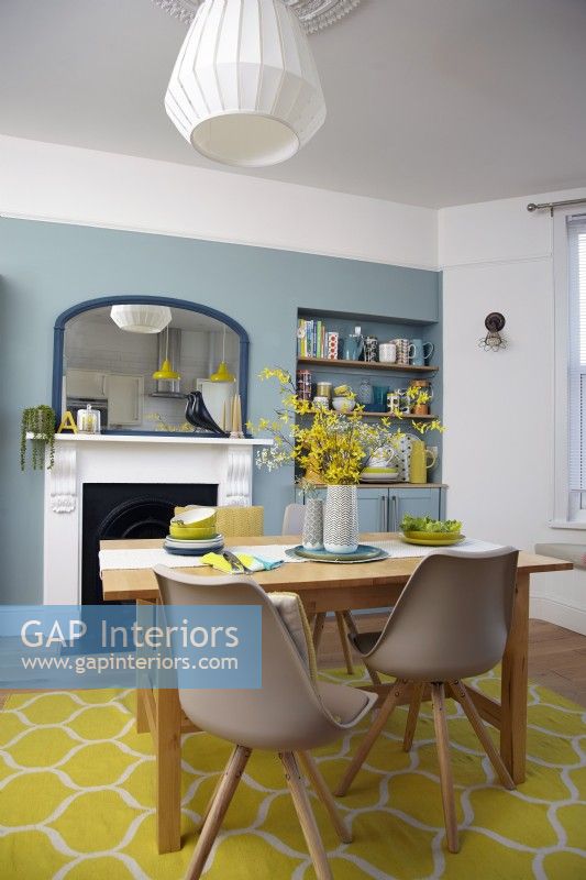 Cuisine-salle à manger ouverte avec des murs bleus, une cheminée victorienne et un tapis jaune.