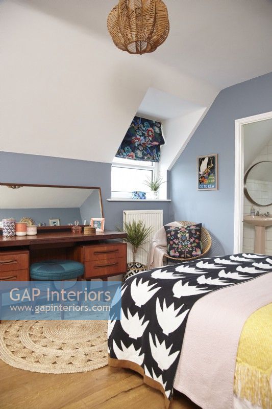 Chambre avec salle de bain attenante, murs peints en bleu et mobilier du milieu du siècle.