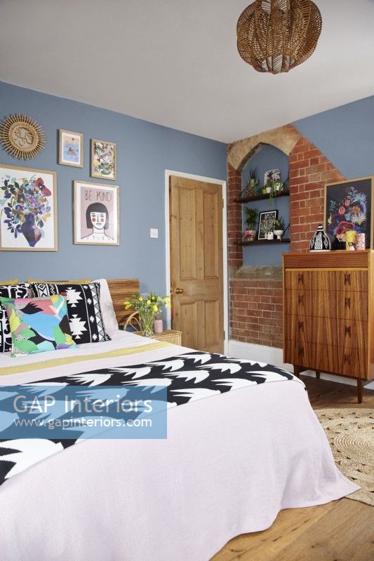 Chambre avec briques apparentes d'origine, murs peints en bleu et mobilier rétro.