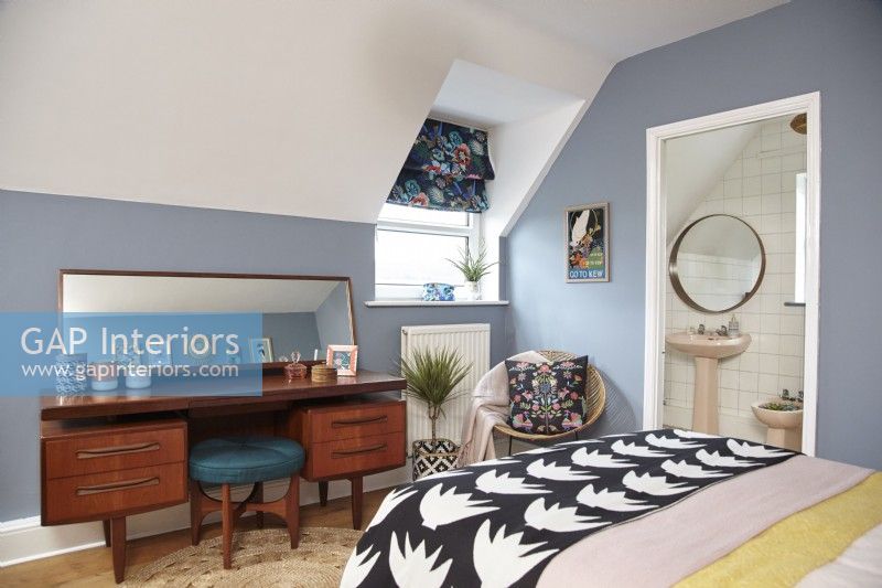Chambre avec salle de bain attenante, murs peints en bleu et mobilier du milieu du siècle.