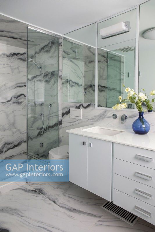 Salle de bains blanche moderne avec sol et murs à motifs en marbre.