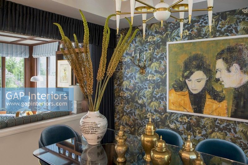 Salle à manger décorée avec papier peint à motifs floraux et peinture de Steve McQueen et Jacqueline Bisset.