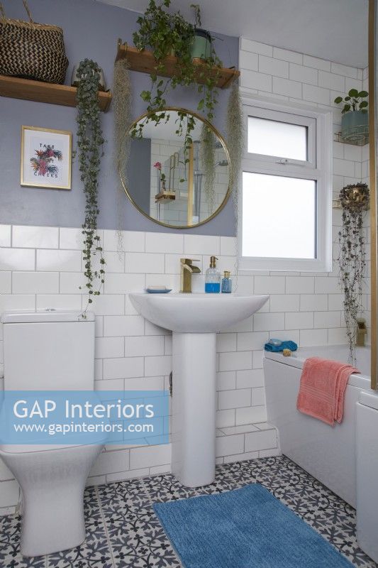 Salle de bain avec carrelage blanc, murs gris, sol à motifs et étagères ouvertes.