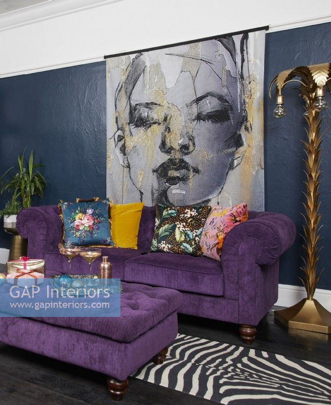 Salon aux murs bleu foncé, canapé violet et grand poster illustré d'une femme.