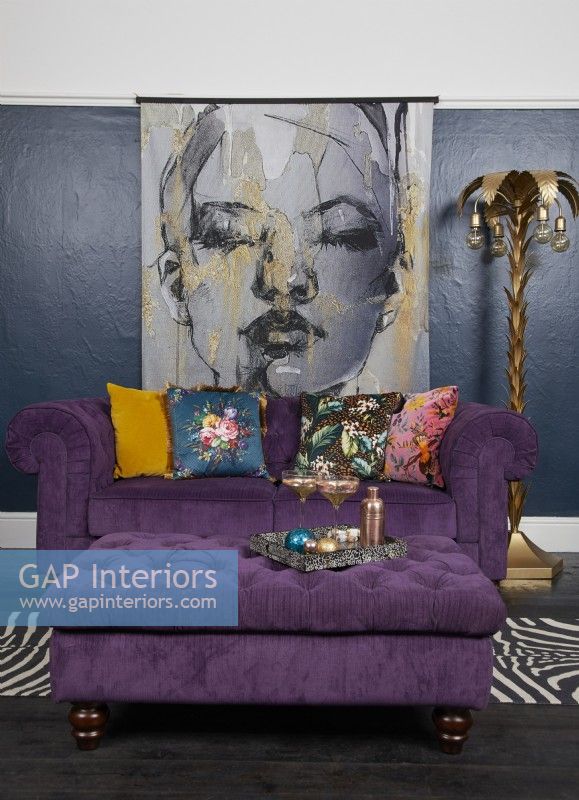 Salon aux murs bleu foncé, canapé violet et grand poster illustré d'une femme.