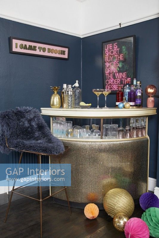 Salon avec un bar à boissons doré, des murs peints en bleu foncé et des décorations de Noël.