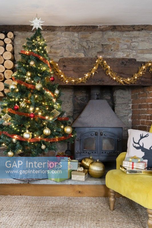 Maison de campagne salon avec arbre de Noël et poêle à bois dans un cantou en pierre et brique