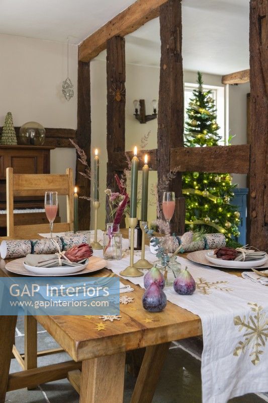 Coin repas avec table à manger en bois dressée pour Noël devant poutres apparentes