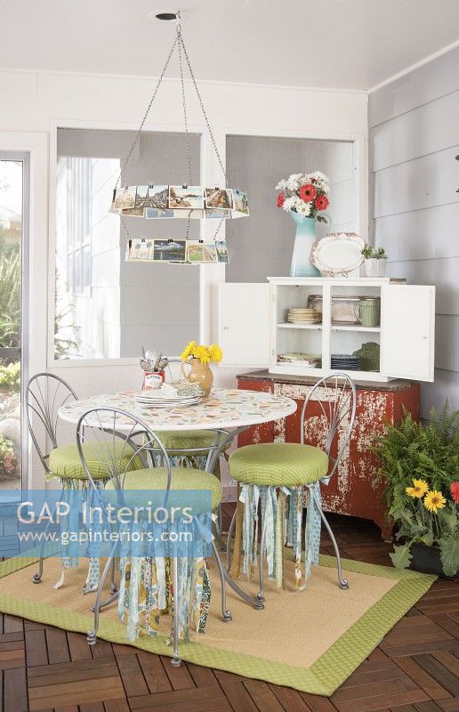 Salle à manger du porche 3 saisons avec table peinte, lustre de carte postale vintage et armoire de rangement