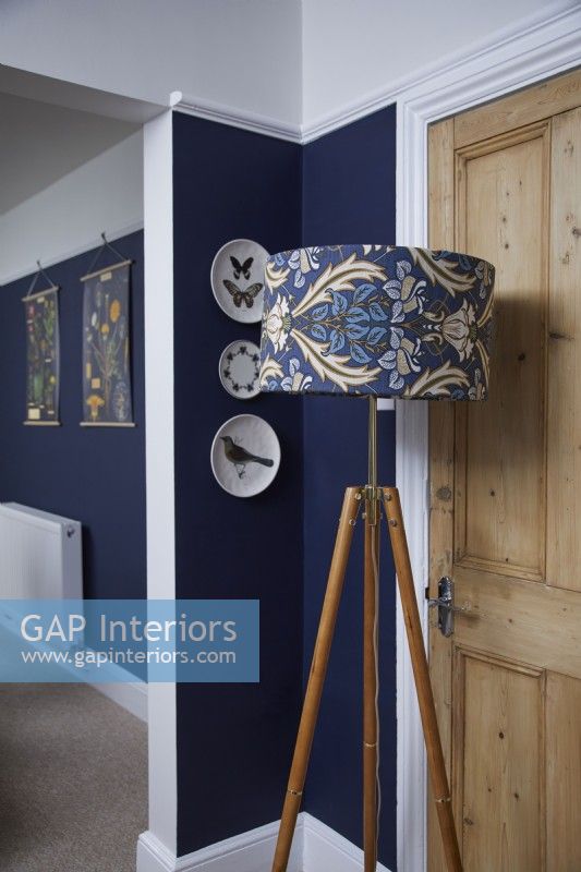 Détail du salon montrant un lampadaire à motifs, avec des murs peints en bleu foncé.