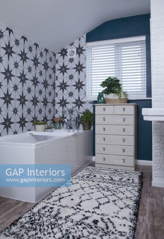 Salle de bain avec carreaux à motifs, murs peints en bleu et ensemble de tiroirs vintage.