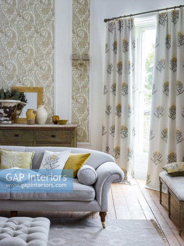 Salon avec canapé gris, papier peint à motifs et rideaux