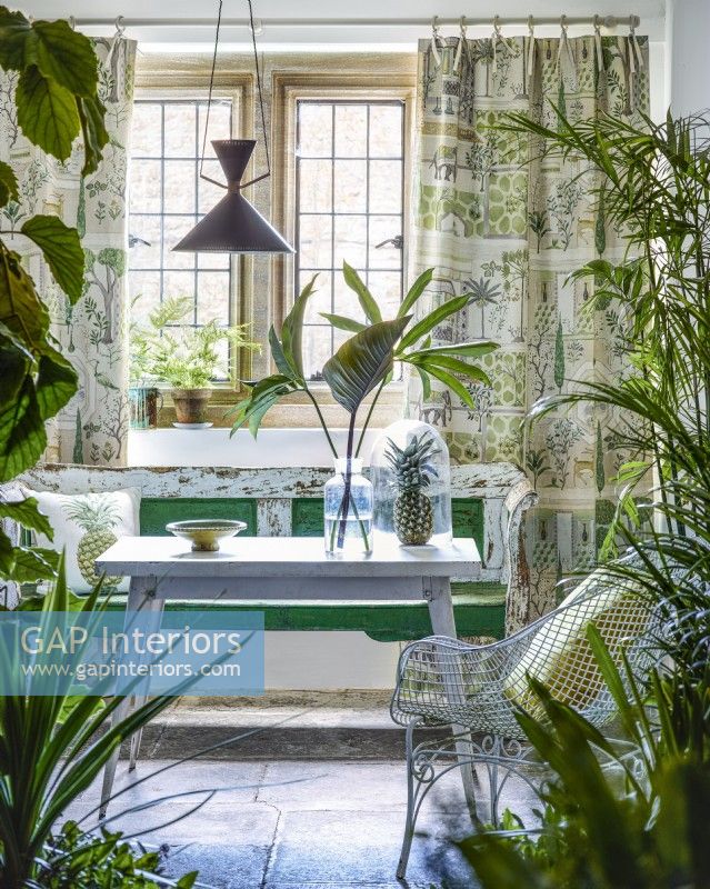 Véranda d'époque avec plantes d'intérieur, banc et table