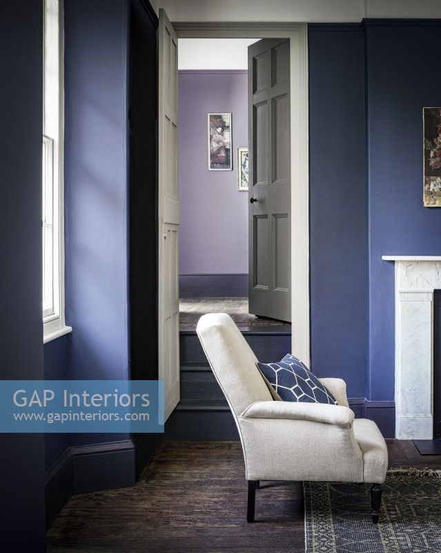 Salon peint en violet/bleu avec une chaise à partir de la porte