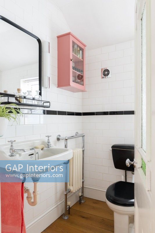 Salle de bain carrelée blanche et noire avec meuble mural rose
