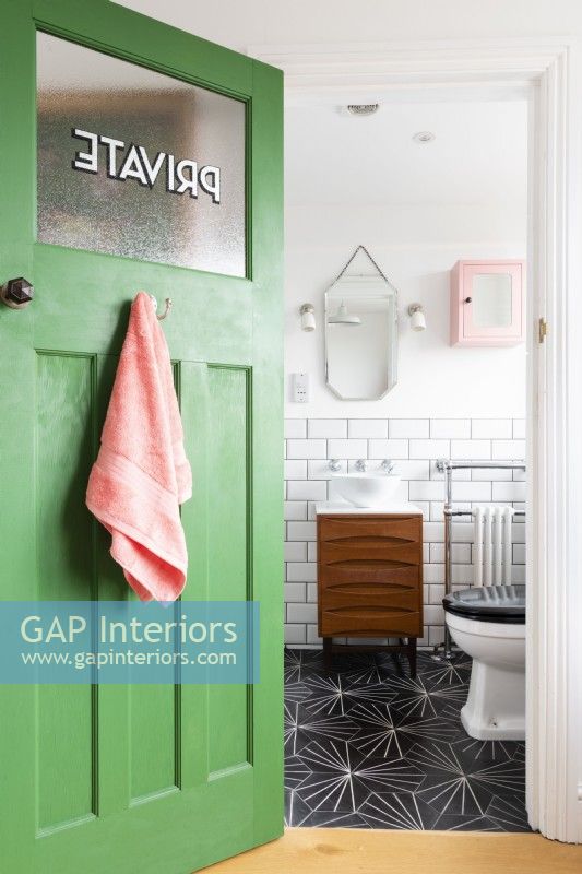 Porte verte récupérée s'ouvrant sur une salle de bains avec armoire à tiroirs du milieu du siècle convertie en meuble-lavabo avec lavabo