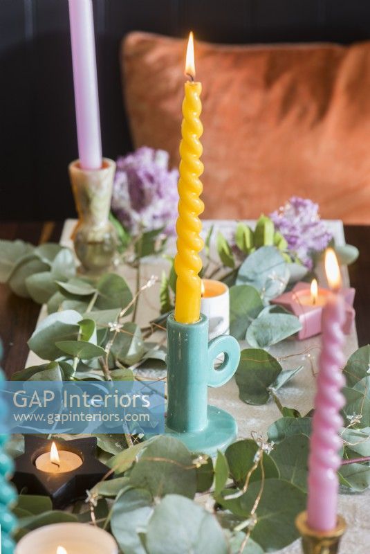 Bougies de couleur pastel et décorations de feuillage sur table à manger