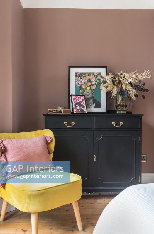 Armoire noire et chaise jaune dans la chambre aux murs peints en rose