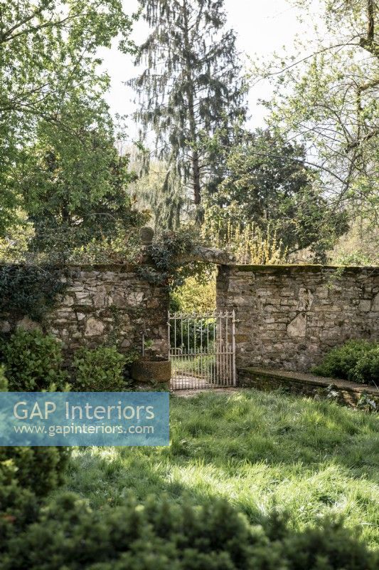 Mur de pierre et portail métallique dans le jardin de campagne