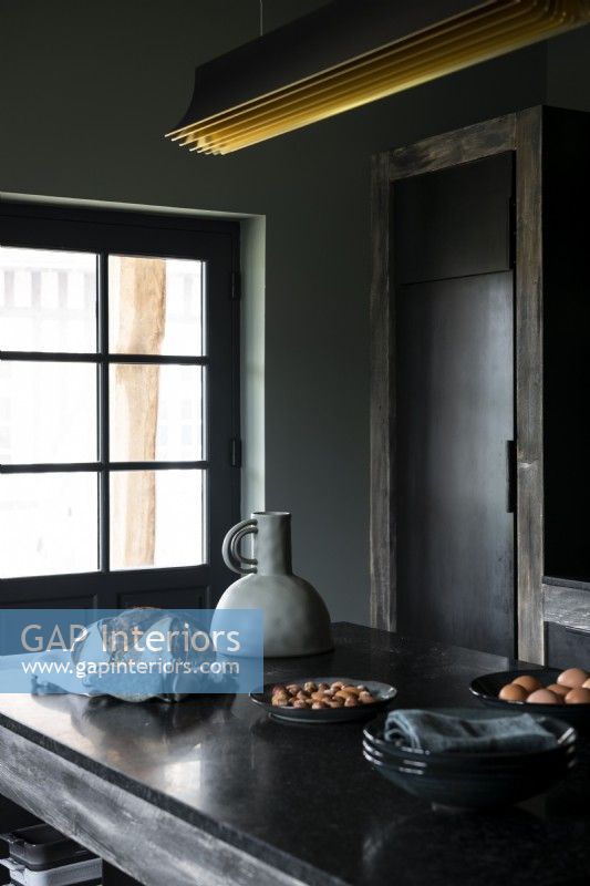 Îlot dans une cuisine de campagne rustique et moderne avec des armoires peintes en noir